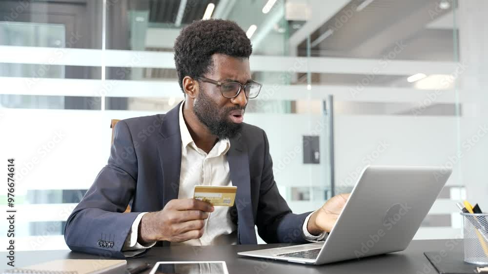 Shocked upset american businessman businessman checks his credit card on laptop while sitting at workplace in business office. Frustrated black man faced fraud or scam. He became a victim of deception Shocked upset american businessman businessman checks his credit card on laptop while sitting at workplace in business office. Frustrated black man faced fraud or scam. He became a victim of deception