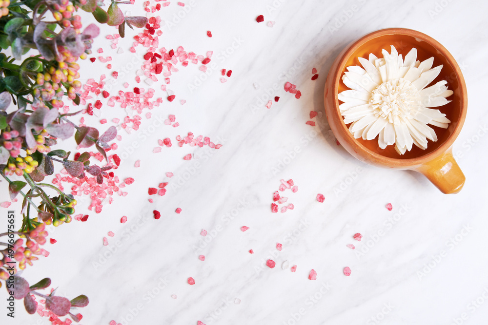 White flower sits in a brown bowl on a marble surface. Pink salt is scattered around the bowl and a sprig of greenery peeks out from the frame White flower sits in a brown bowl on a marble surface. Pink salt is scattered around the bowl and a sprig of greenery peeks out from the frame