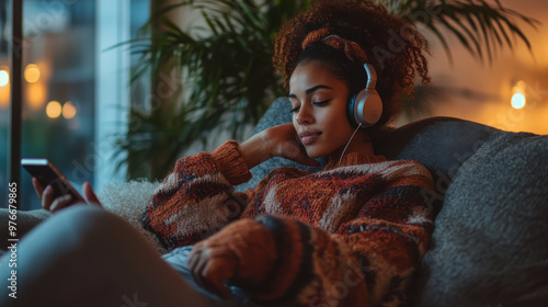 Christmas season is here Young woman at home for Christmas. She is laying down on sofa and listening music on headphones