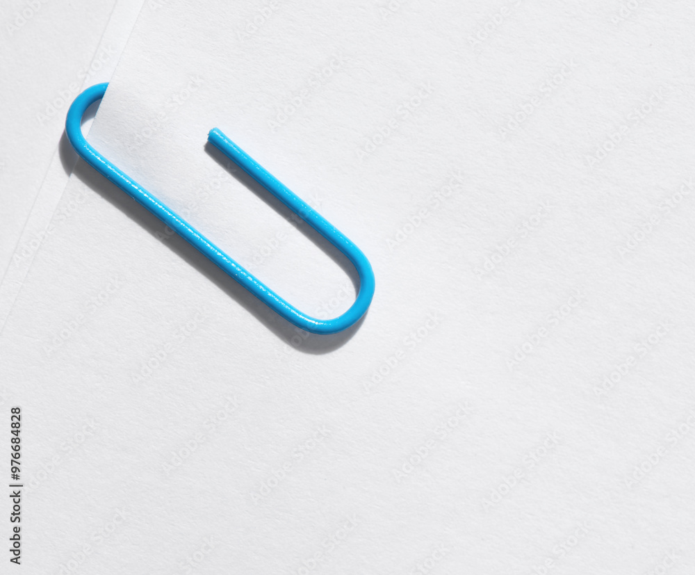 Blue paper clip attached to pile of blank white paper. Blue paper clip attached to pile of blank white paper.