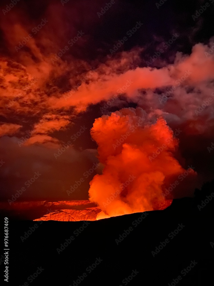 A cloud of smoke, bathed in an orange glow, rises above a volcanic eruption at Kīlauea volcano. A cloud of smoke, bathed in an orange glow, rises above a volcanic eruption at Kīlauea volcano.