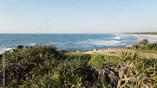 Low drone view travelling over a coastal headland revealing a hidden surf beach in Australia photo