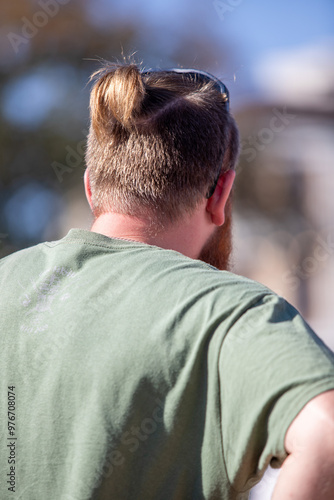 A man with a green shirt and a ponytail