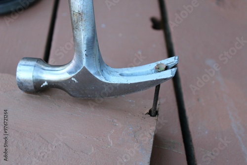 hammer taking nail out of brown wood board home repair photo