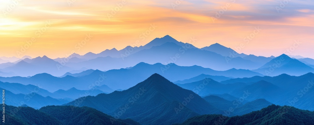 Obraz premium A serene mountain landscape with layered peaks fading into the distance under a colorful sunset sky.