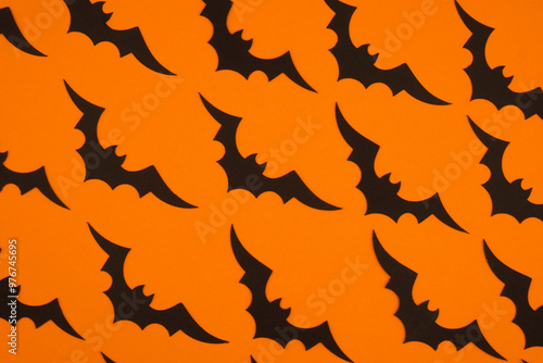 Spooky black bats flying across a bright orange background for Halloween decoration