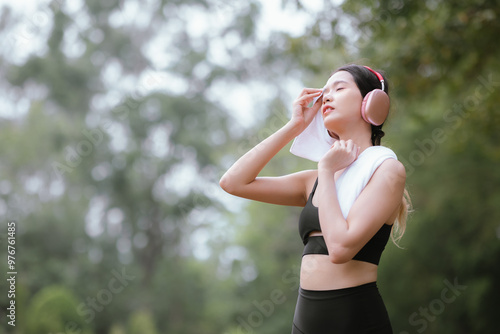 A fit and confident Asian woman jogs through an urban city park, embracing a healthy, active lifestyle with athletic determination, endurance, and vitality during her daily fitness routine.