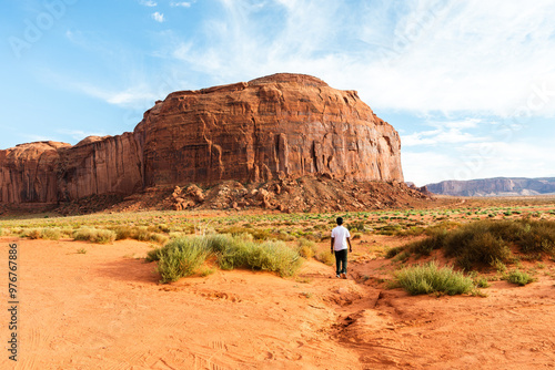 Man walking toward a massive sandstone formation in Monument Valley photo