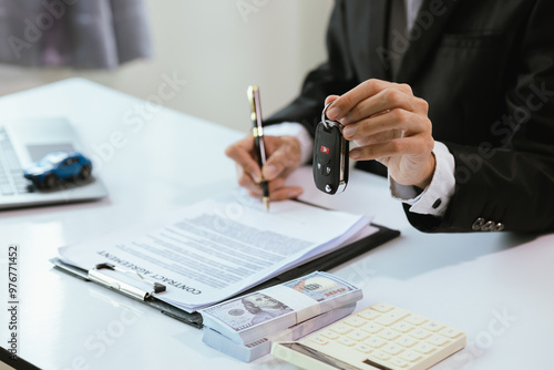 Obraz na plátně A satisfied customer signs paperwork at a car dealership, finalizing the purchase of a new vehicle