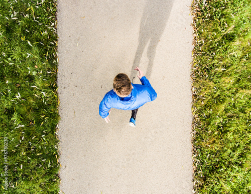 Aerial view of a runner running through autumn park on jogging path. Morning running training. photo