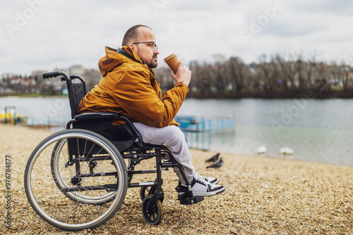 Paraplegic handicapped man in wheelchair is enjoying outdoor and drinking coffee. photo