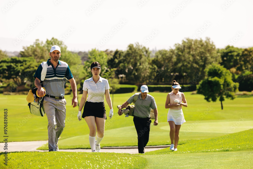 Fototapeta premium Group of golfers with golf bags walking on a golf course during a match