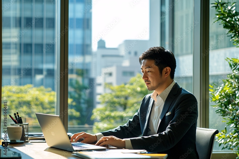 A focused businessman working on a laptop in a modern office with large windows, showcasing a bright and productive atmosphere. A focused businessman working on a laptop in a modern office with large windows, showcasing a bright and productive atmosphere.