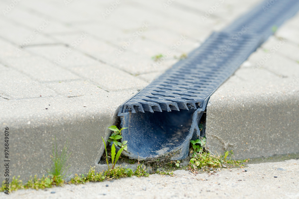 Channel drain system with plastic grate on paved road. Stormwater management. Durable plastic trench drain closeup. Channel drain with PVC grid grating, lightweight and robust drainage system.