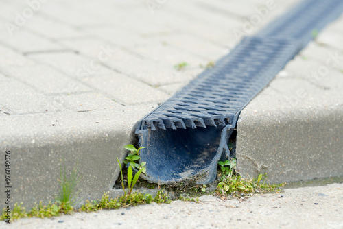 Obraz na płótnie Channel drain system with plastic grate on paved road. Stormwater management. Durable plastic trench drain closeup. Channel drain with PVC grid grating, lightweight and robust drainage system. w salonie