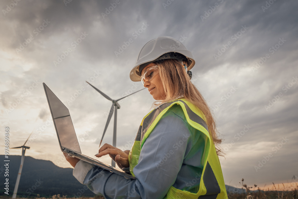 A skilled female engineer is conducting vital research at a modern wind farm, using advanced technology on her laptop to improve sustainability and drive innovation in engineering A skilled female engineer is conducting vital research at a modern wind farm, using advanced technology on her laptop to improve sustainability and drive innovation in engineering