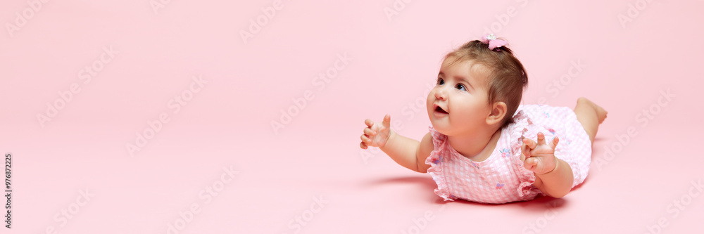 Banner. Sweet baby girl with curious eyes shining as she crawls forward against soft pink background with negative space. Concept of beauty, parenthood, childhood, life and birth. Banner. Sweet baby girl with curious eyes shining as she crawls forward against soft pink background with negative space. Concept of beauty, parenthood, childhood, life and birth.