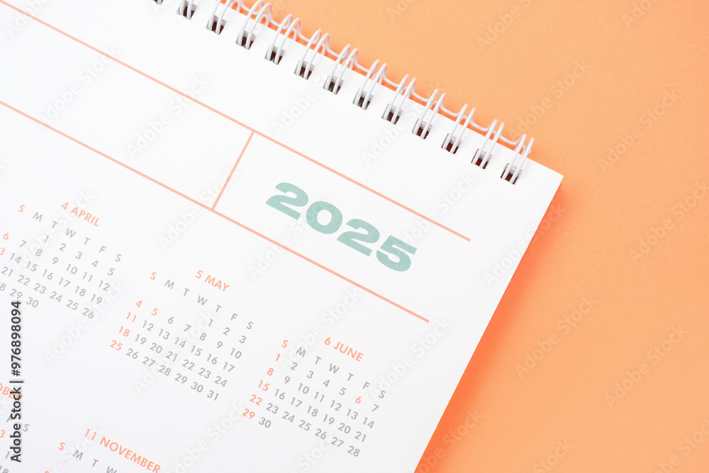 White calendar 2025 on orange background close-up, planning concept. White calendar 2025 on orange background close-up, planning concept.