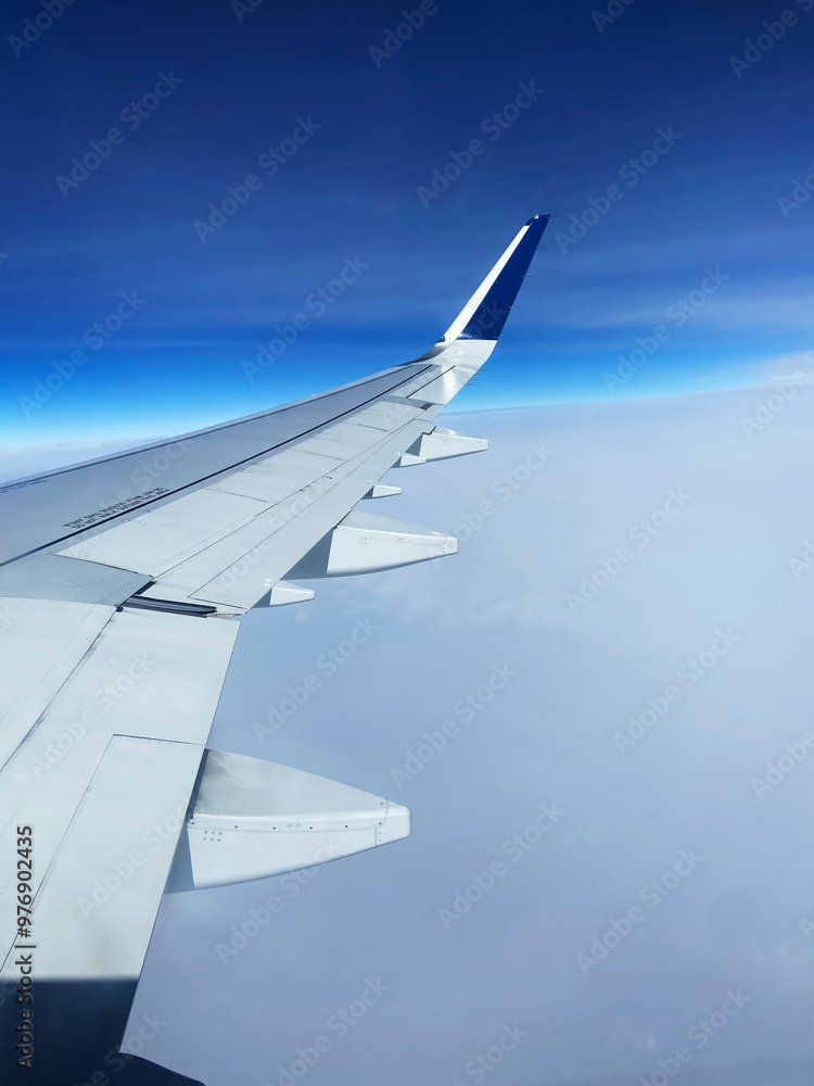 Fototapeta premium Airplane wing flying above the clouds on sunny day