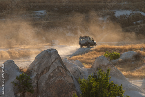 In Cappadocia, at sunset, there is a stunning view of the valley, along which a jeep is driving, raising clouds of dust behind it.Turkey
