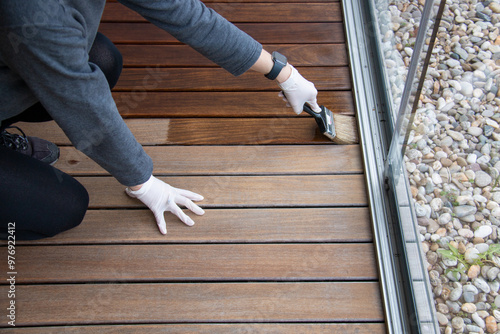 Wood floor sealing and varnishing, hand holding a brush applying transparent protective coat