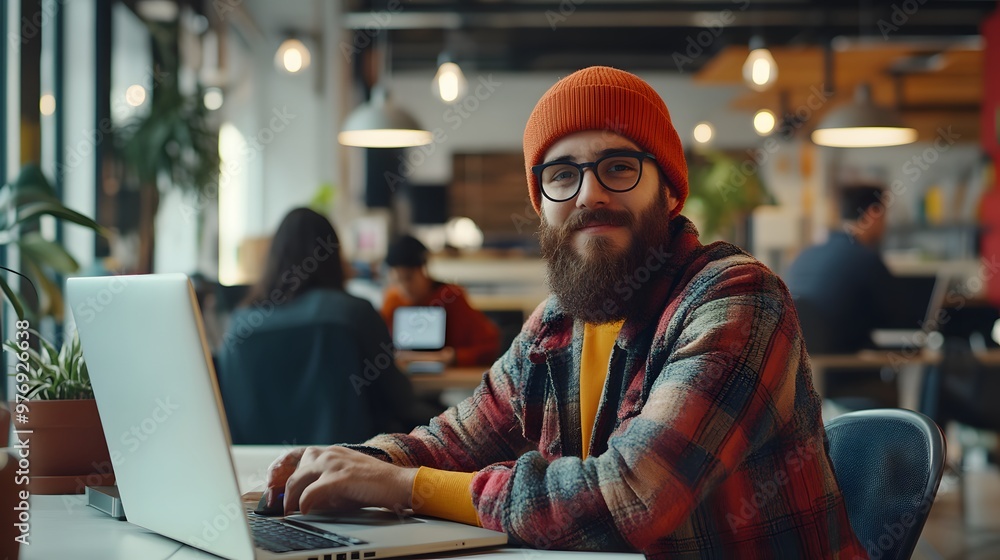 Bearded Man in Red and Yellow Plaid Shirt Works on Laptop in an Office