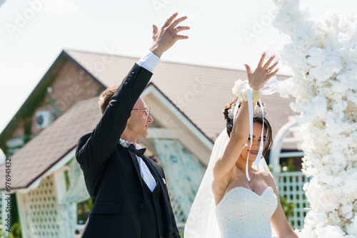 Obraz na plátně Elegant Outdoor Wedding Ceremony with Joyful Couple Under Floral Arch