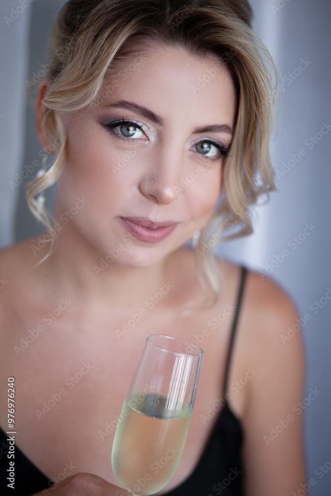 A portrait of a beautiful bride with stylish makeup, a thin arrow and nude lips holds a glass. A girl with an evening hairstyle, a high bun on blond hair, dressed wedding dress A portrait of a beautiful bride with stylish makeup, a thin arrow and nude lips holds a glass. A girl with an evening hairstyle, a high bun on blond hair, dressed wedding dress