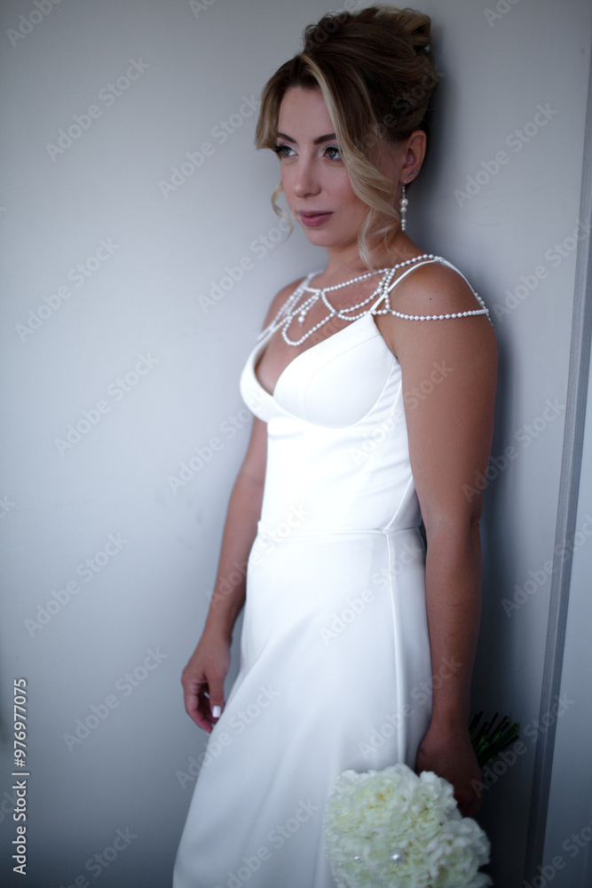 A portrait of a beautiful bride with stylish makeup, a thin arrow and nude lips holds a bouquet. A girl with an evening hairstyle, a high bun on blond hair, dressed wedding dress A portrait of a beautiful bride with stylish makeup, a thin arrow and nude lips holds a bouquet. A girl with an evening hairstyle, a high bun on blond hair, dressed wedding dress