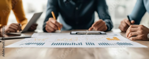 A group of professionals collaborating on data analysis, sharing insights over a chart-filled document on a wooden table. photo