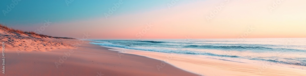 Deserted beach at dawn with smooth sand and calm ocean under pastel sky Deserted beach at dawn with smooth sand and calm ocean under pastel sky