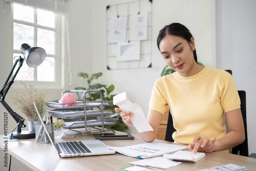 Young Woman Working at Home Office Desk with Laptop, Calculator, and Documents in Bright Modern Workspace Young Woman Working at Home Office Desk with Laptop, Calculator, and Documents in Bright Modern Workspace