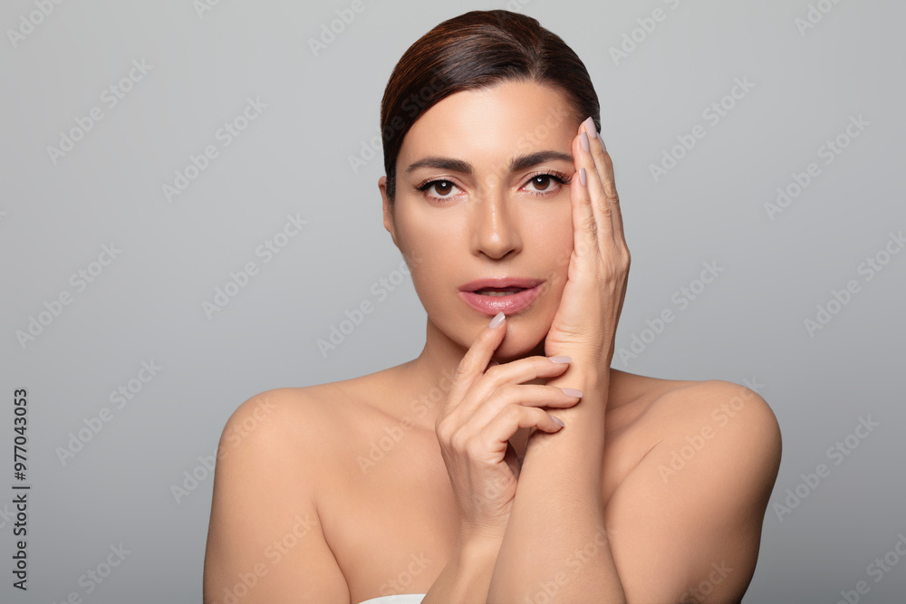 Beautiful natural 50's woman posing for a skincare advertisement, isolated on gray background Beautiful natural 50's woman posing for a skincare advertisement, isolated on gray background