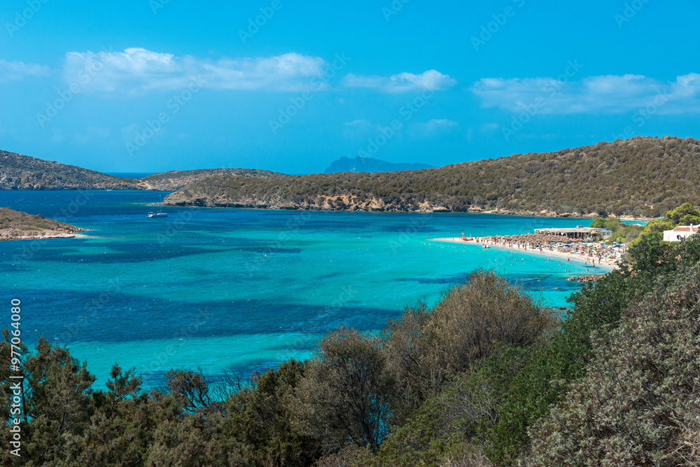Fototapeta premium View of emerald sea and white beach, Boat anchored in the bay in the background - Tuerredda, Sardina