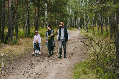 Happy family on a walk in the forest picking berries and herbs, traveling along paths and stones mom dad and children