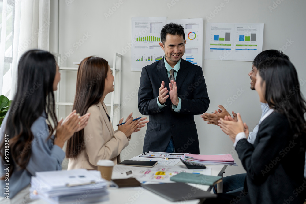 A group of people are clapping and smiling at a man in a suit A group of people are clapping and smiling at a man in a suit
