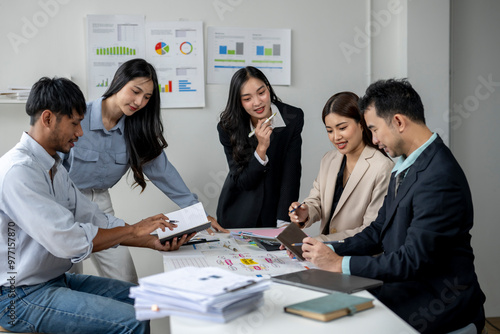 A group of people are sitting around a table with papers and a laptop