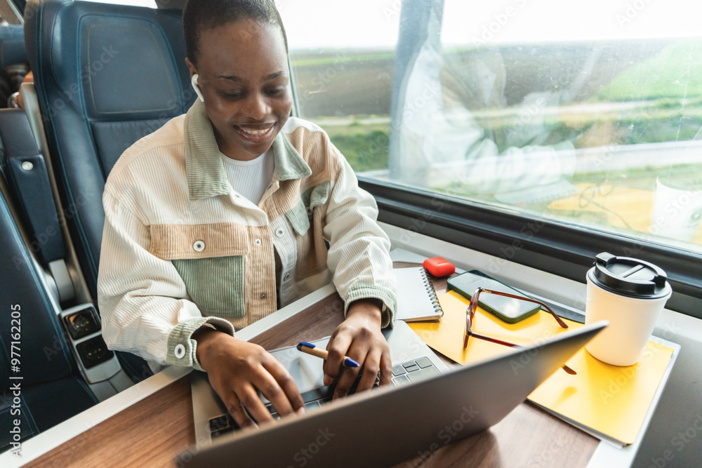 Young businesswoman working on laptop in public bus. She is sitting on the seat near the window and typing. Young businesswoman working on laptop in public bus. She is sitting on the seat near the window and typing.