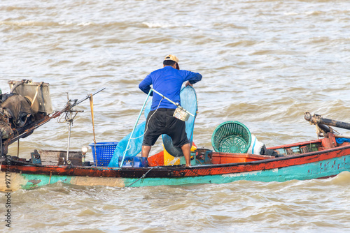 A fisherman on a boat catches fish, Thailand photo