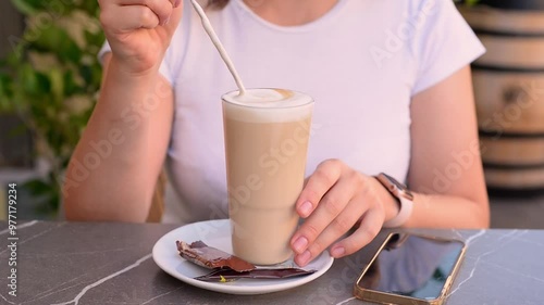 Young woman drinking coffee or cappuccino in cafe close-up