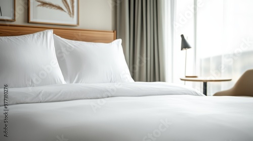 A cozy hotel bed is positioned near a window with sheer white curtains, allowing sunlight to flood the room and create a warm and inviting atmosphere, perfect for resting.