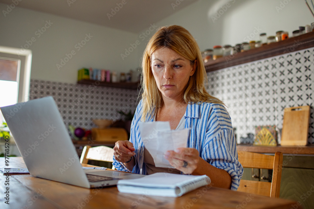 Woman feeling stressed while reading bills at home Woman feeling stressed while reading bills at home