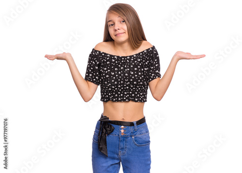 Teen girl in a black floral crop top and blue jeans shrugging her shoulders with a confused expression, isolated on white.