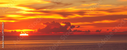 Vibrant sunset over calm ocean waters with dramatic clouds on the horizon photo