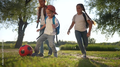 Schoolchildren playing a game of ball in their backpacks. Kid sport boy concept. Group of kids playing soccer at school. Group of kids playing soccer in their backpacks lifestyle with schoolchildren. photo