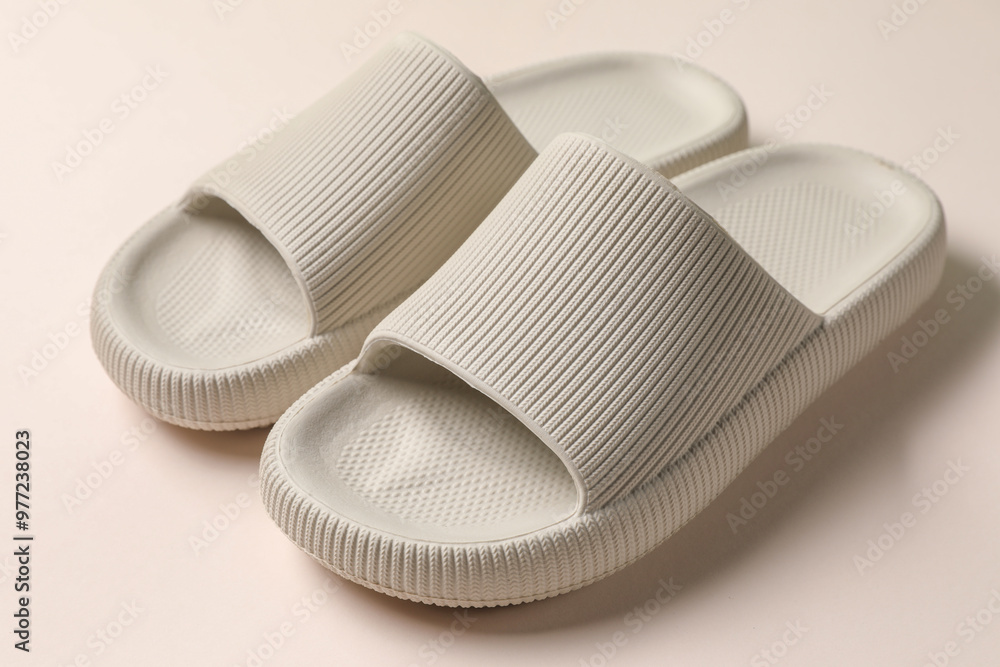 Pair of rubber slippers on beige background, closeup Pair of rubber slippers on beige background, closeup