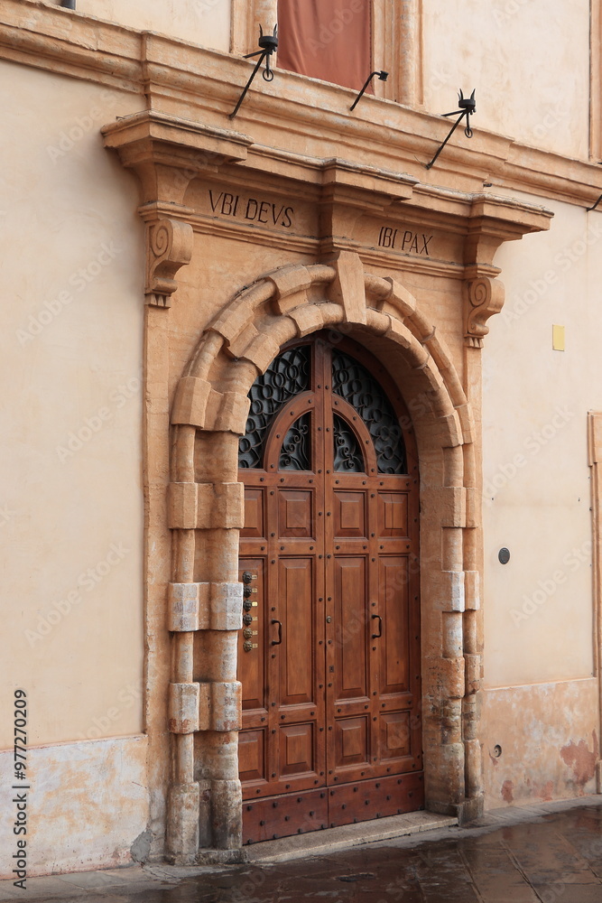 Naklejka premium Wooden Building Entrance with Sculpted Stone Frame in Assisi, Italy