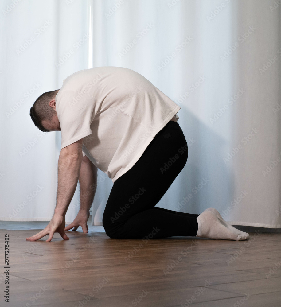 Home yoga pose workouts. A man performs sports exercises with his legs and arms. Male athlete stretches. Home yoga pose workouts. A man performs sports exercises with his legs and arms. Male athlete stretches.