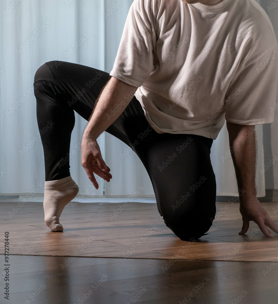 Warming up the feet in the dance studio. A man stretches his toes. Guy's dance pose. Warming up the feet in the dance studio. A man stretches his toes. Guy's dance pose.