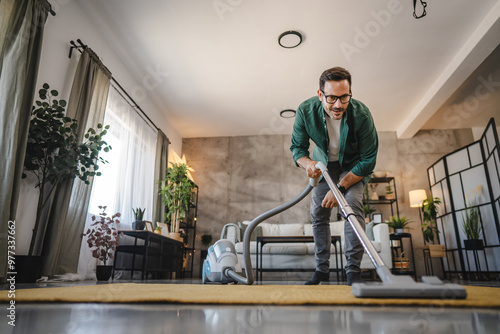 Foto Adult man vacuum living room with modern decor and natural light